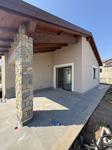 Portico esterno della villa con pilastro in pietra e serramenti installati