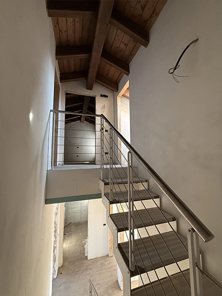 Scala interna con parapetto metallico e tetto in legno a vista