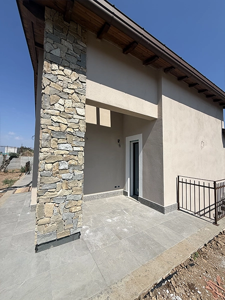 Ingresso esterno della villa con portico e rivestimento in pietra